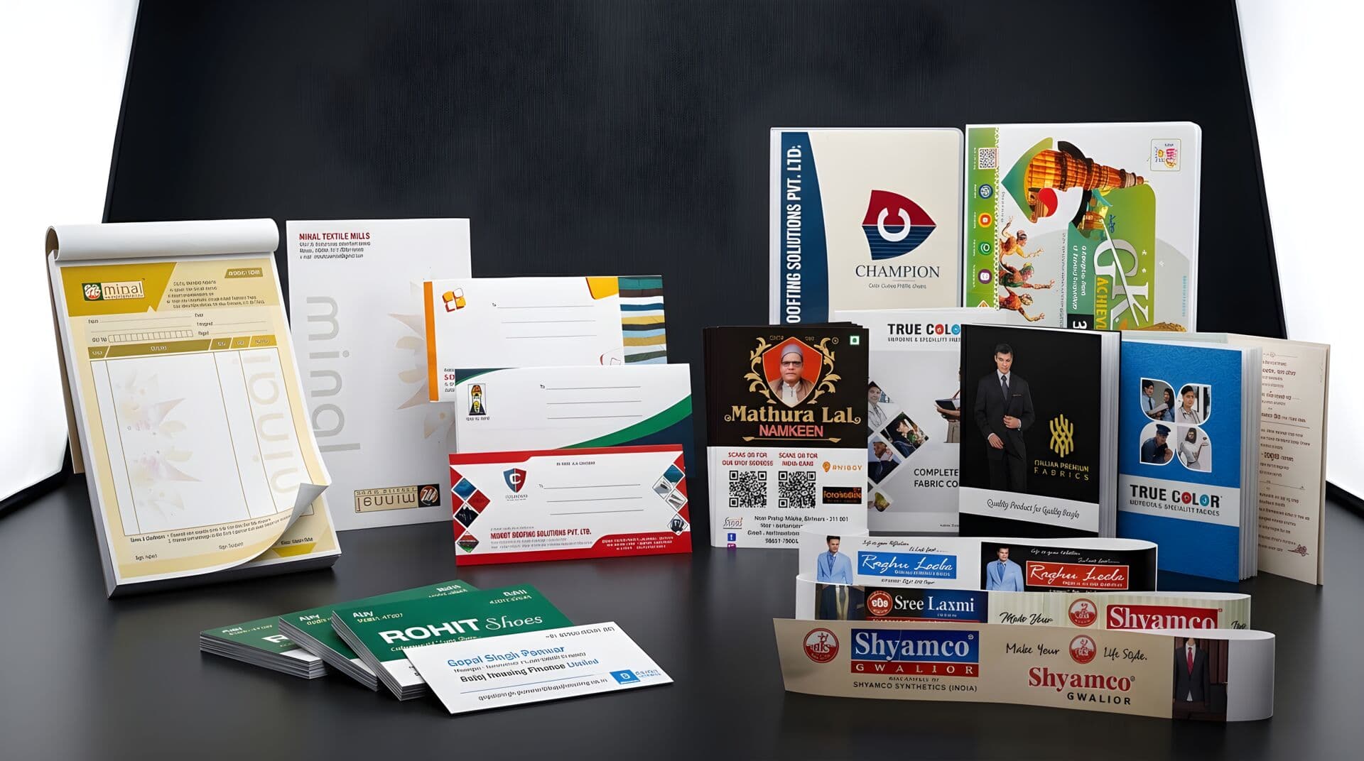 Premium print samples — brochures, business cards, and catalogues arranged on a dark surface, showcasing Global Printers' offset printing quality
